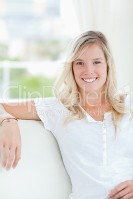 A smiling woman sitting on the couch as she looks into the camer