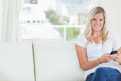 A smiling woman looking at the camera with a mobile phone in her