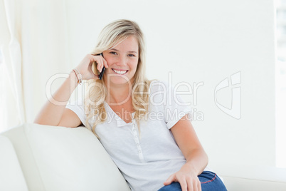 Side view of a woman on her couch smiling as she talks on the ph