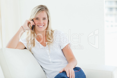 A woman talking on her phone while smiling and looking at the ca