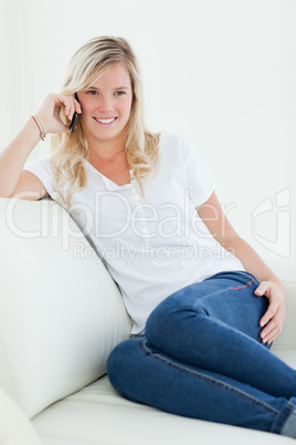A woman sitting on the couch with her mobile as she talks and lo
