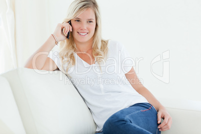 A woman talking on the phone and smiling as she looks to the sid