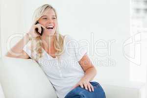 A laughing woman on her phone as she sits on the couch