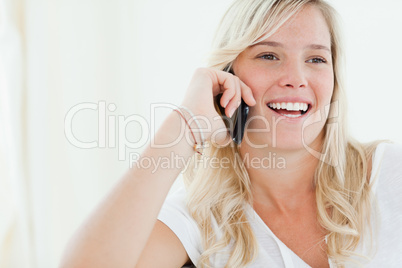 Close up of a woman laughing on her phone as she looks to the si