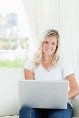 A smiling woman holding a laptop as she looks at the camera