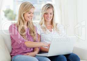 Two smiling women using a laptop as one points to the screen