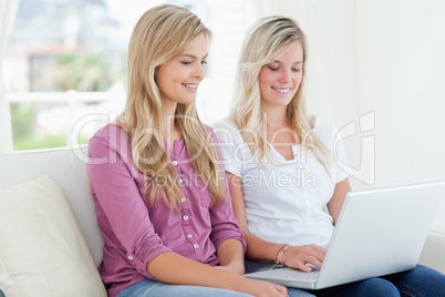 Women sitting together on the couch with a laptop smiling