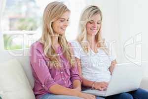 Women sitting together on the couch with a laptop smiling