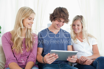 Three friends sit together as they look at a tablet pc