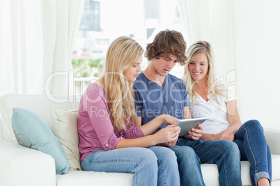 Borther and sisters sit on the couch while looking at a tablet p