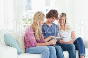 Borther and sisters sit on the couch while looking at a tablet p