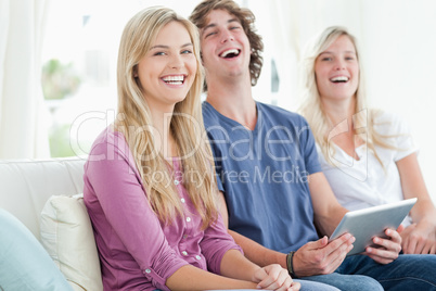 Laughing group of friends sitting as they use a tablet