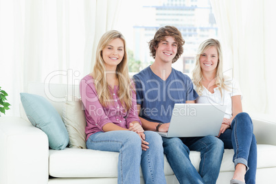 Smiling people on the couch as they use the laptop
