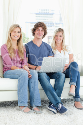 A group of friends sitting together as they use a laptop