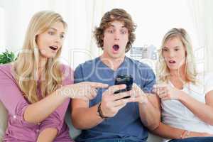 People on the couch shocked at what is on the phone