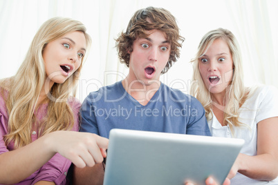 Three shocked friends looking at the screen of the tablet