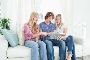 Three friends looking at the screen of the tablet in shock and p