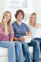 Three friends eating popcorn while smiling and about to change t