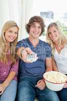 Three friends eating popcorn together as they look at the camera