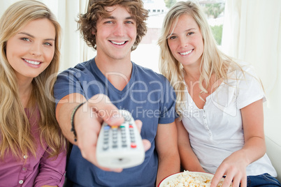 Focus shot on three friends as they use the remote to change the