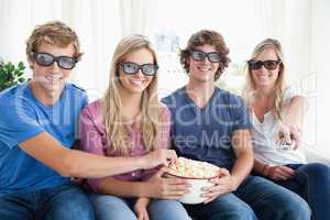 Friends smiling as they eat popcorn and watch a 3d movie