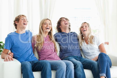 Laughing friends sit on the couch together