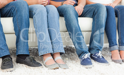 Four pairs of feet beside one another against the couch