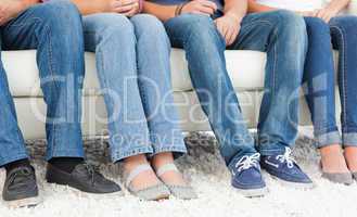 Four pairs of feet beside one another against the couch