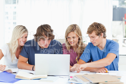 A group of students use a laptop to answer their questions