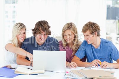 A female student points to the screen as the group use the lapto