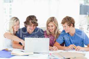 A female student points to the screen as the group use the lapto