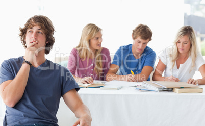 A young man sitting in front of his working class mates and thin