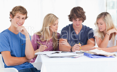 A group of students sitting together as they all study as one sm