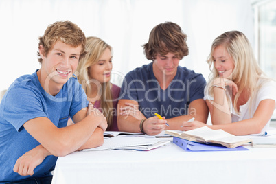 A group of students sitting together as they all study as one si