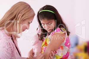 Doctor give injection to girl's arm, focus on the little girl.