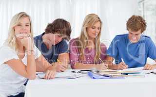 A study group working hard as one girl smiles and looks at the c