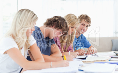 A group of students working as one student looks at the camera w