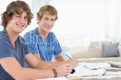 A pair of male students smiling as they both look at the camera