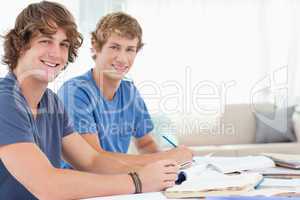 A pair of male students smiling as they both look at the camera