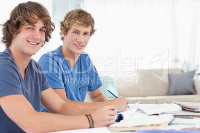 Side view of two students looking into the camera and smiling