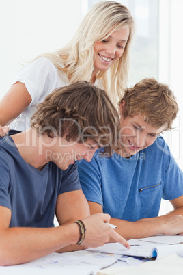 Two smiling students studying together as a girl stands overhead