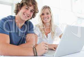 A smiling couple with a laptop looking at the camera