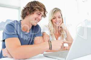A smiling couple look at the laptop together