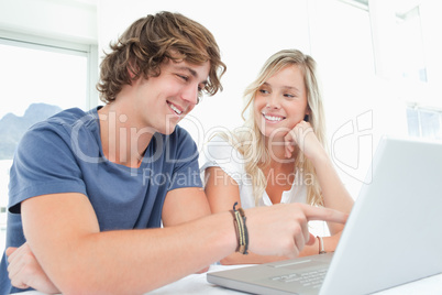 A smiling couple looking at the laptop with the woman looking at