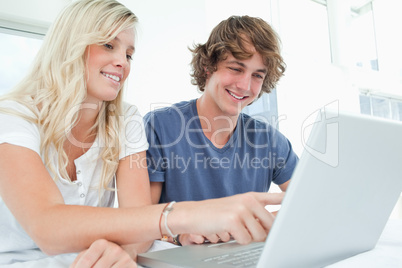 A smiling couple using a laptop while pointing at the screen