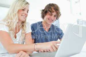 A smiling couple using a laptop while pointing at the screen
