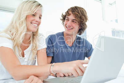 A couple use a laptop with a man looking at the woman