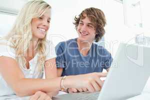 A couple use a laptop with a man looking at the woman