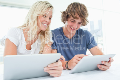 A man and woman both using their tablets