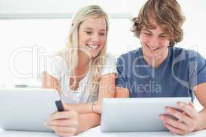 A smiling girl looks into her boyfriends tablet